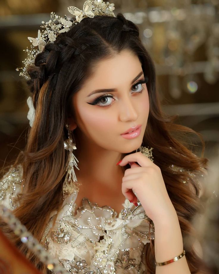 a beautiful young woman wearing a tiara and holding her hand to her face while looking at the camera