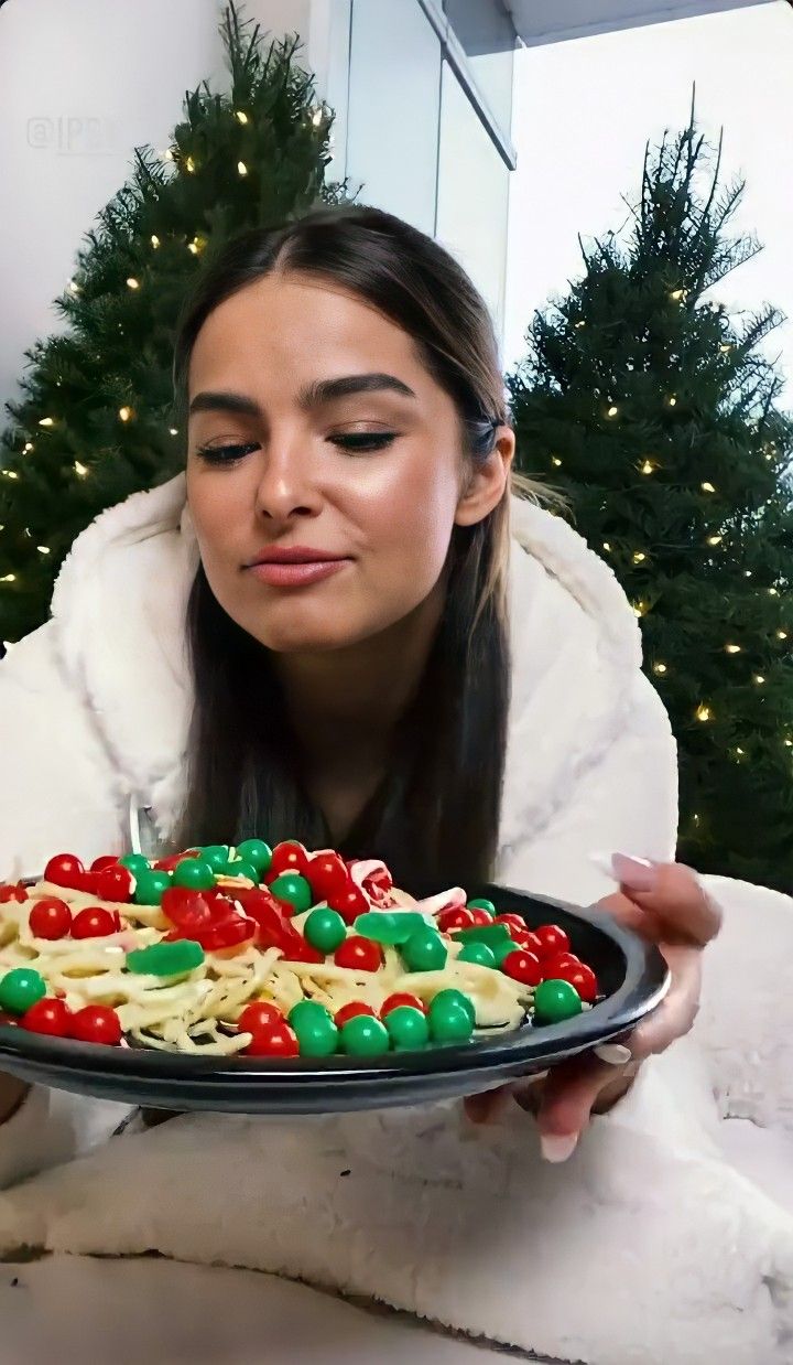 a woman is holding a plate with christmas cookies on it