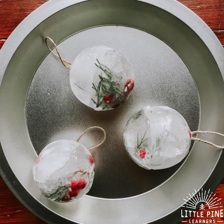 three glass ornaments are sitting on a metal plate