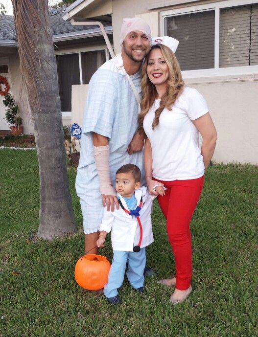 a man and woman standing next to a little boy in front of a palm tree