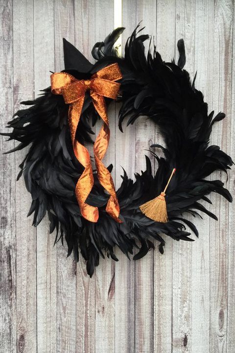 a black wreath with orange ribbons hanging on a wooden fence next to a white door