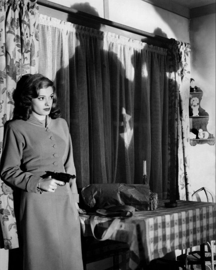 an old photo of a woman standing in front of a table with food on it