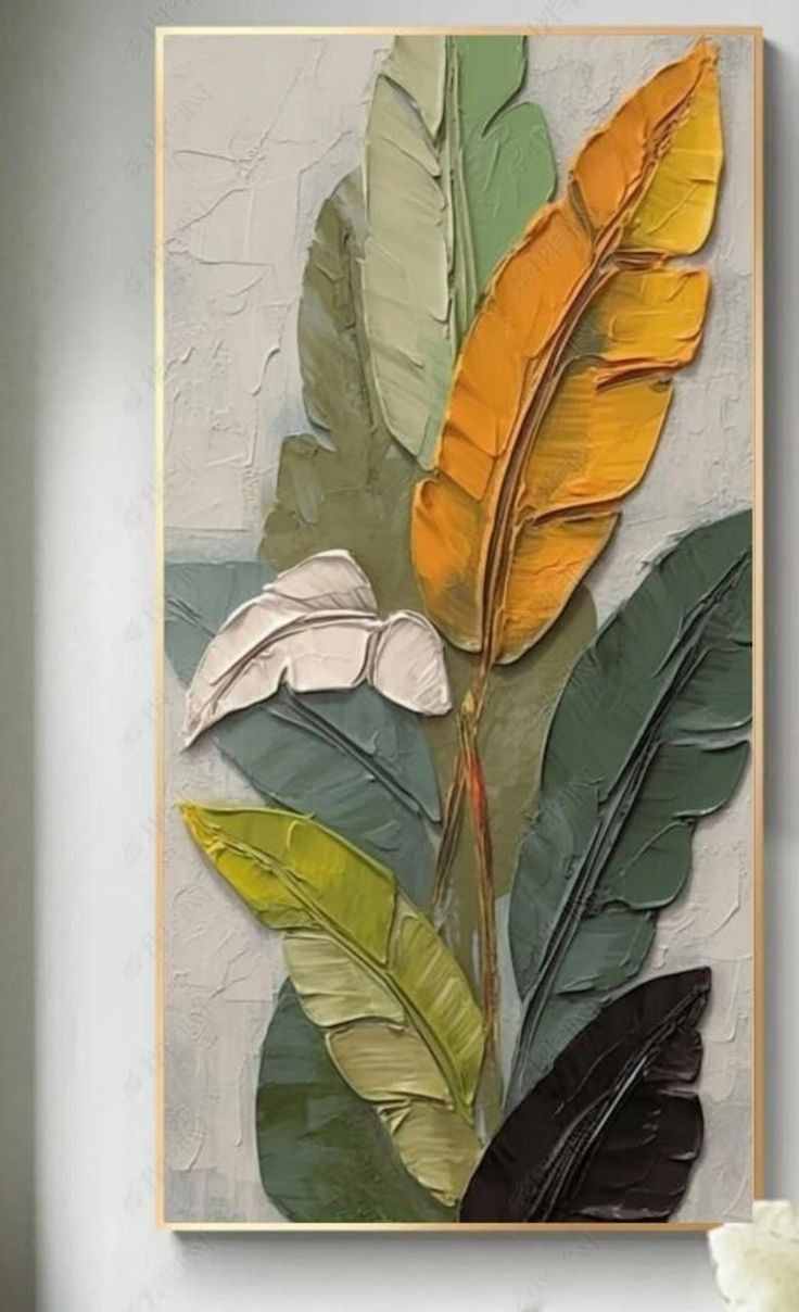 a painting with yellow and green leaves hanging on the wall above a white vase filled with flowers