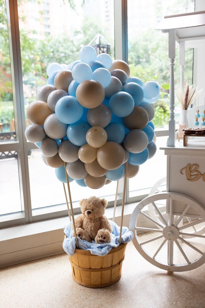 a teddy bear sitting in a basket with balloons