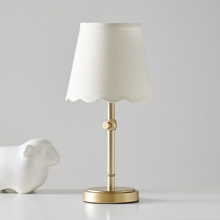 a white elephant lamp sitting next to a gold base with a white shade on it