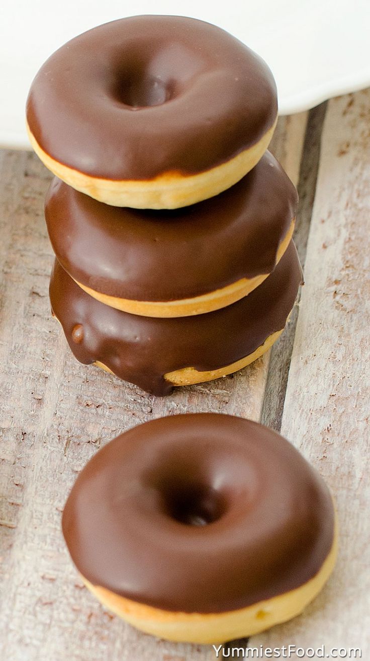 three chocolate covered donuts sitting on top of a wooden table