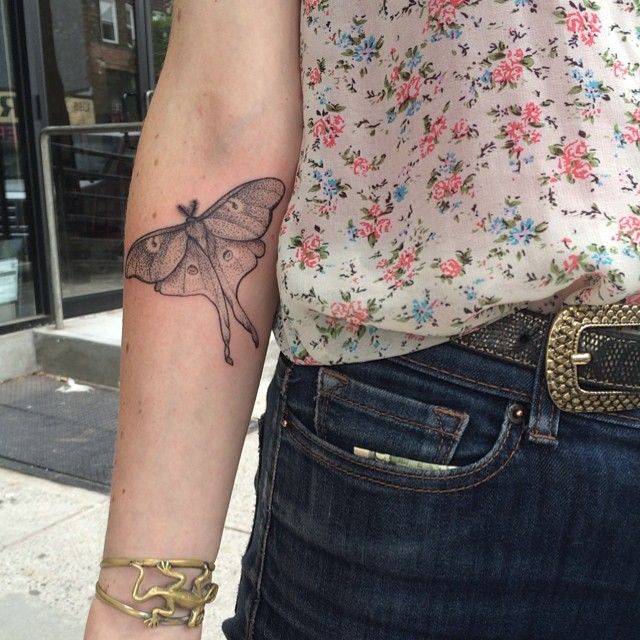 a woman's arm with a butterfly tattoo on the left side of her arm