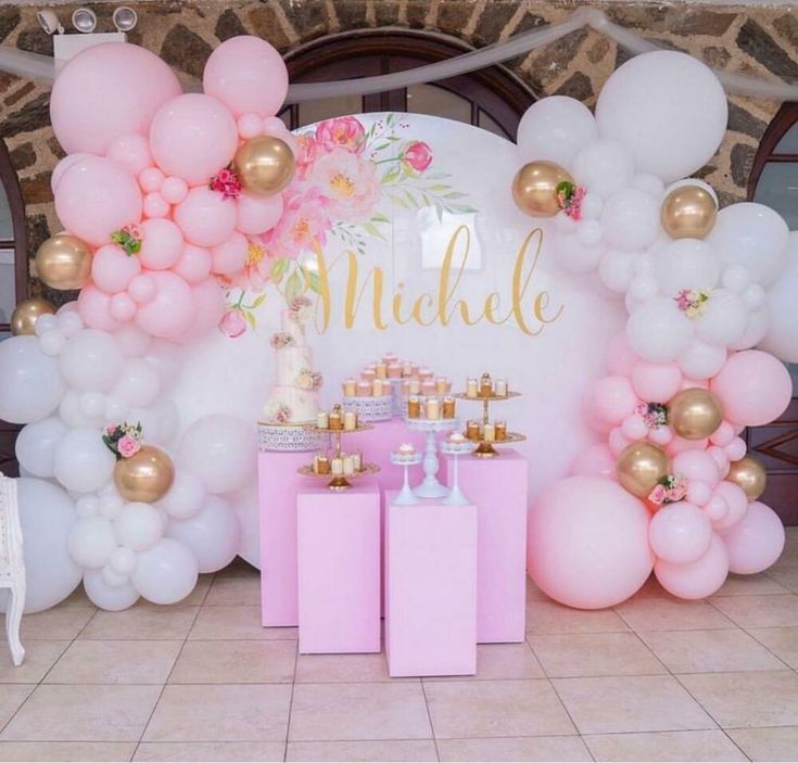 a pink and gold birthday party with balloons on the wall, cake table and decorations