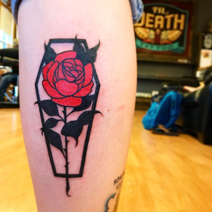 a tattoo on the leg of a woman with a red rose in a black box