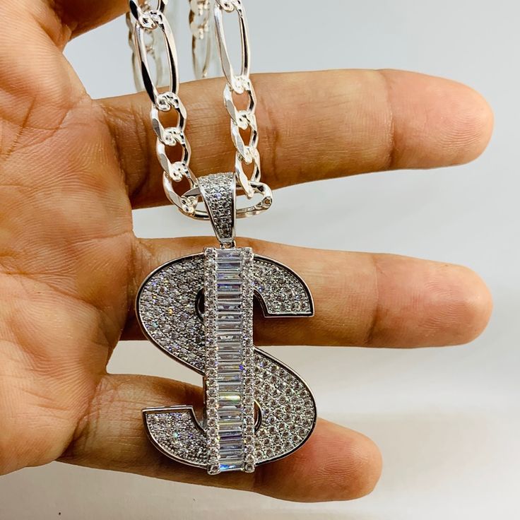 925 Sterling Silver Pendant Money Sign & Figaro Necklace Charm Is 1.5” In Length With White Cubic Zirconia Chain Is 24” & 6.3mm Wide With Diamond Cut On One Side And Plain Opposite Dije Medalla De Plata Dollar Y Cadena Figaro De 24 Pulgadas Frosted Faux Diamond New Jewelry Small Box Included Silver Iced Out Pendant Necklace, Silver Iced Out Necklace For Anniversary, White Diamond Jewelry With Polished Finish, Luxury Custom Silver Necklace, Luxury Iced Out Silver Necklace, Silver Diamond Engraved Necklace, Engraved Diamond Silver Necklace, Luxury Silver Custom Necklace For Anniversary, Iced Out White Gold Necklace In Sterling Silver