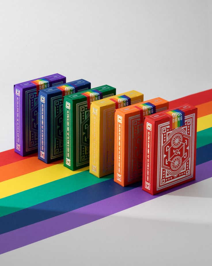 four playing cards are lined up on a rainbow striped surface