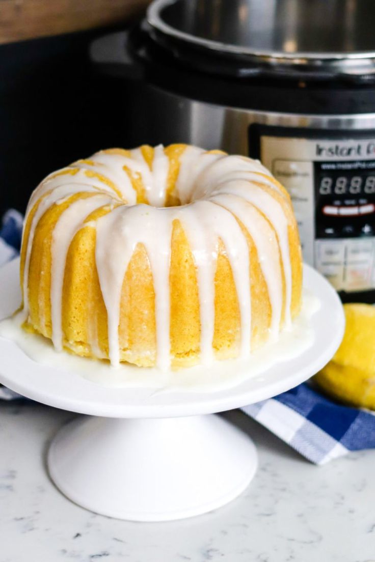 a bundt cake with icing on a plate next to an instant pressure cooker