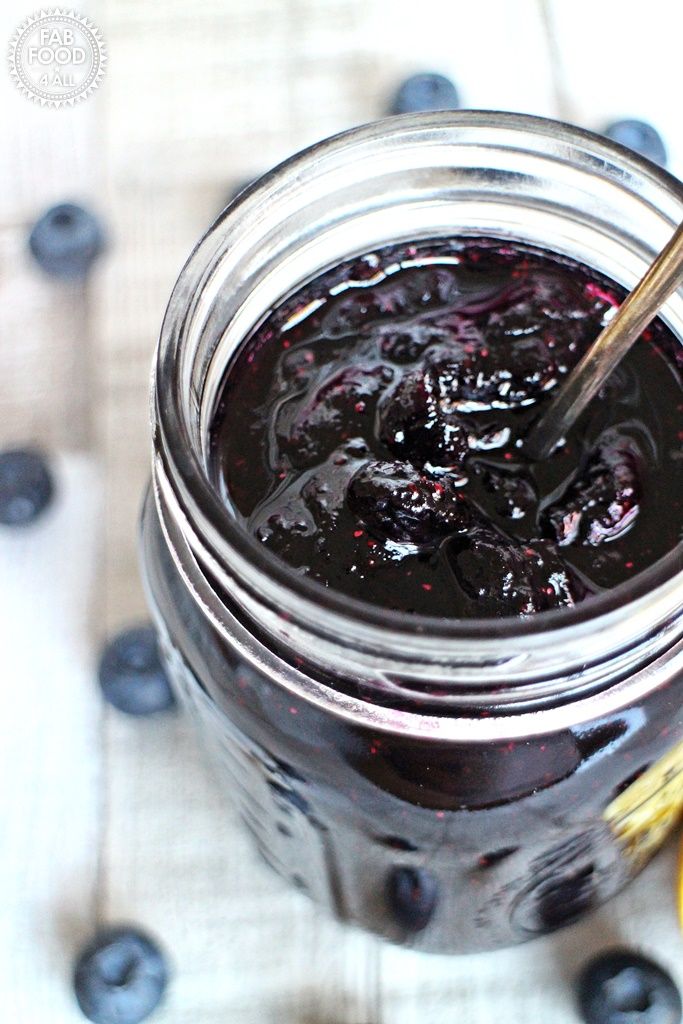 a glass jar filled with blueberry jam on top of a table next to a banana