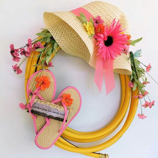 a straw hat and two pairs of flip flops are on a yellow wreath with pink flowers