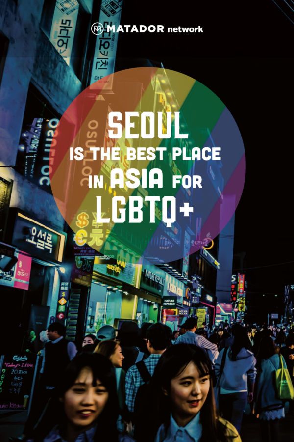 two women standing in the middle of a busy street at night with text that reads seoul is the best place in asia for lgbt