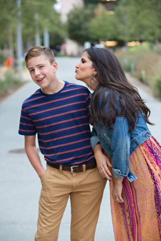 a young man and woman standing next to each other on the side of a road