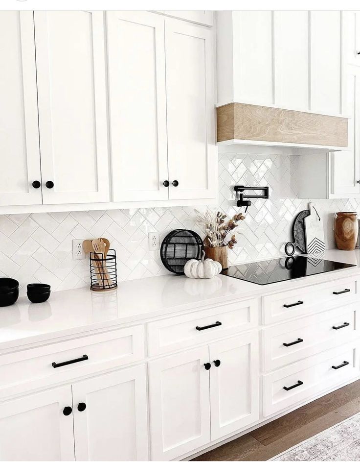 a kitchen with white cabinets and black appliances