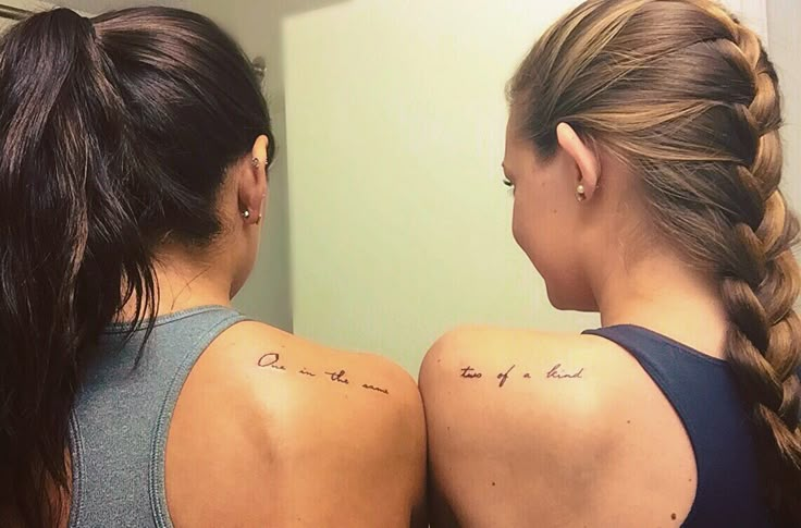 two women with tattoos on their backs looking at each other