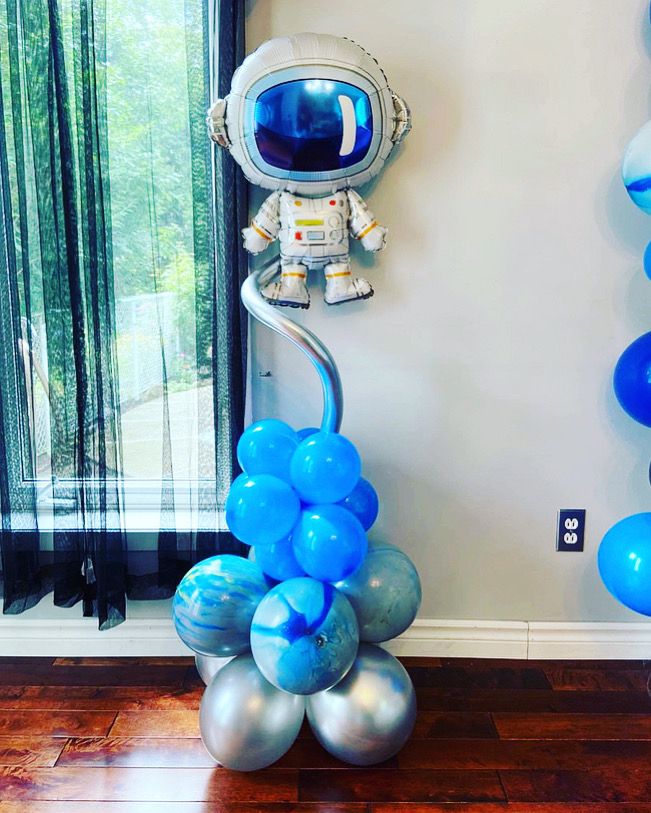 an astronaut balloon decoration with blue and silver balloons