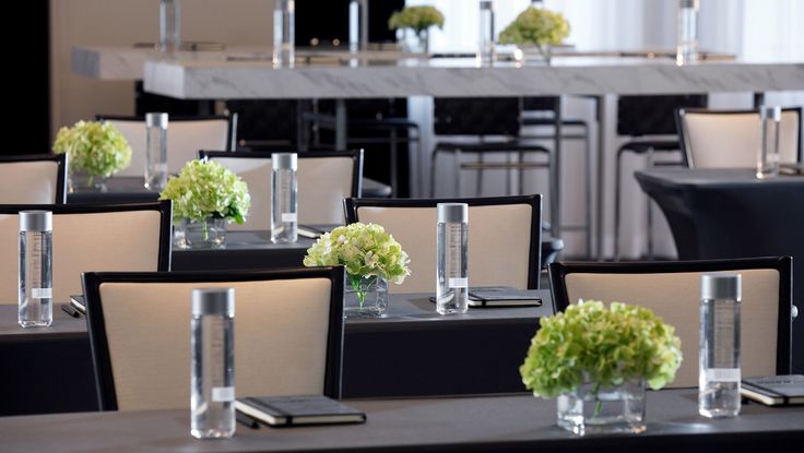 the tables are set up with vases and flowers on them for an elegant dinner