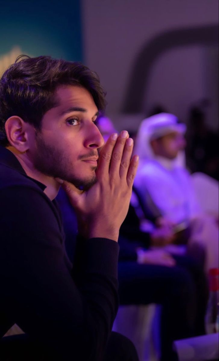 a man in black shirt sitting down with his hands together