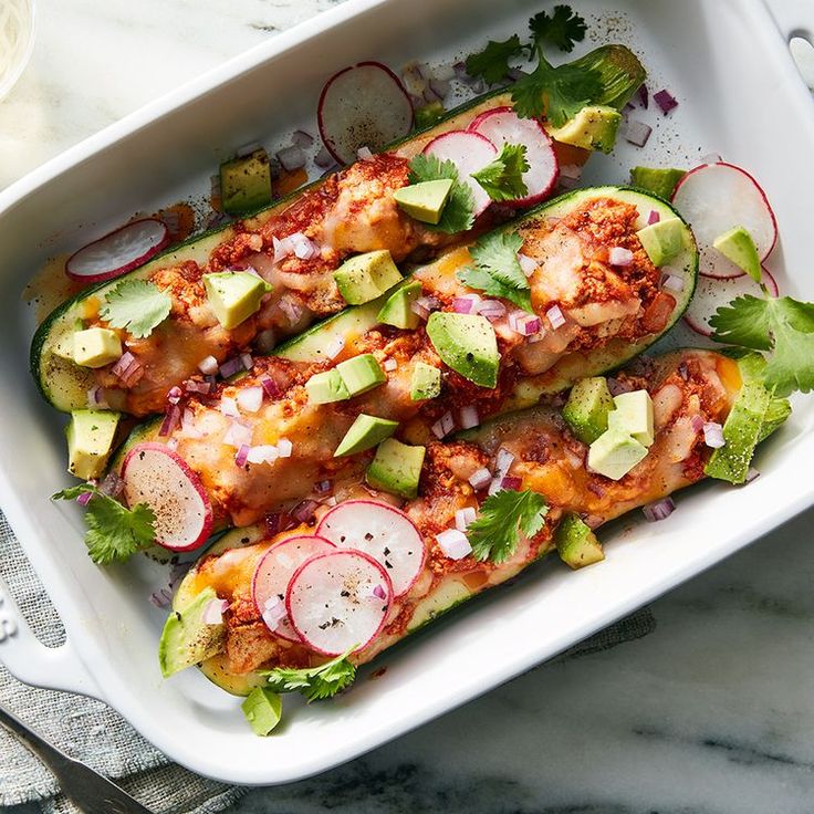 an entree in a casserole dish with sliced radishes and avocado