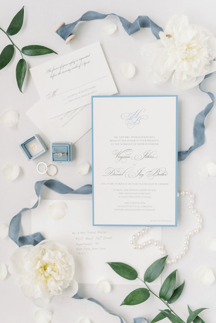 the wedding stationery is laid out with flowers and rings on it's side