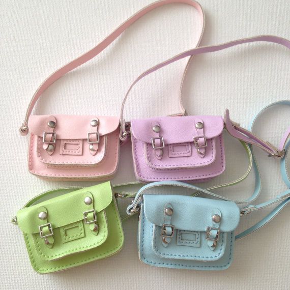 four small purses are lined up on a white surface, one is pink, the other is blue