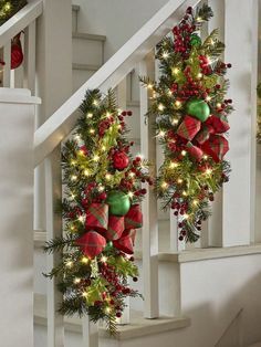 two christmas wreaths are hanging on the banister