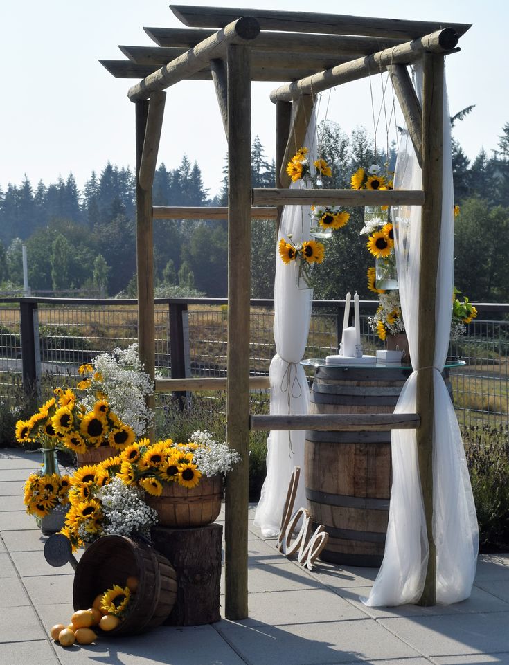 sunflowers and other flowers decorate an outdoor ceremony