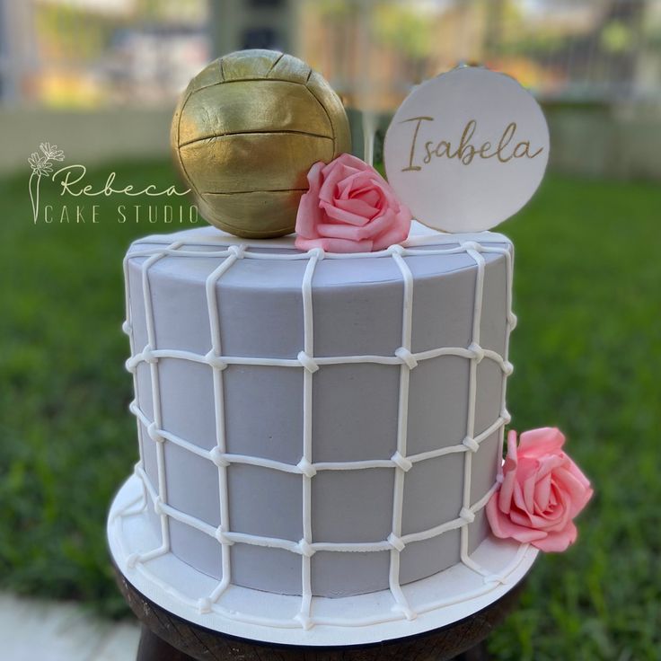 a white cake with pink flowers and a golden ball on top