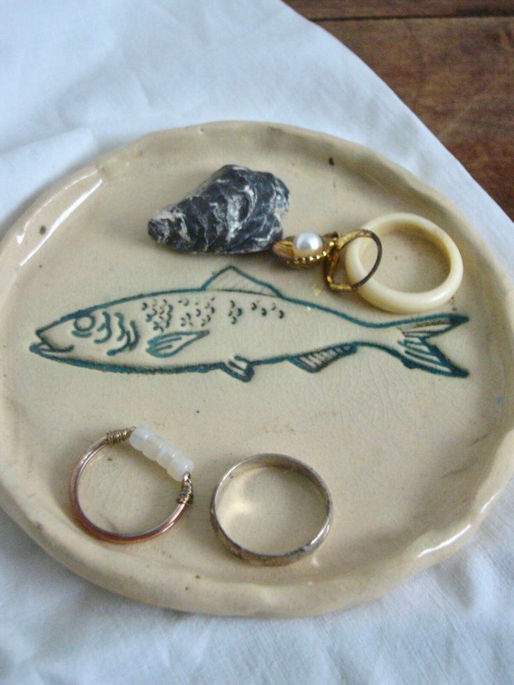 two wedding rings are sitting on a plate next to a pair of scissors and a ring holder