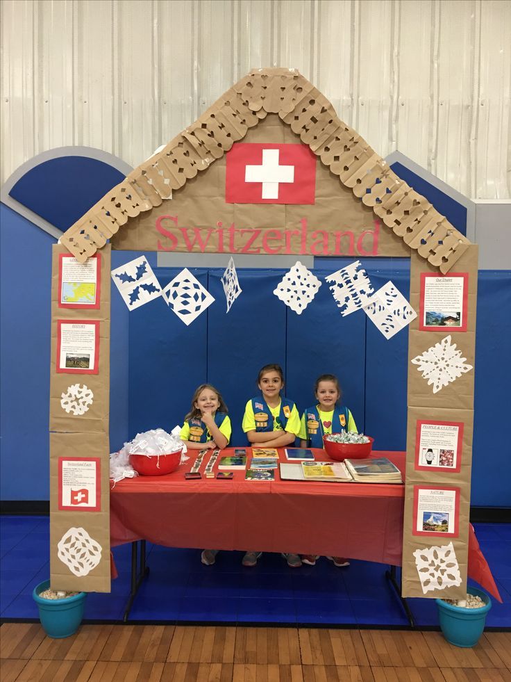 two children are sitting at a table in front of a swiss themed tent with paper cutouts on it