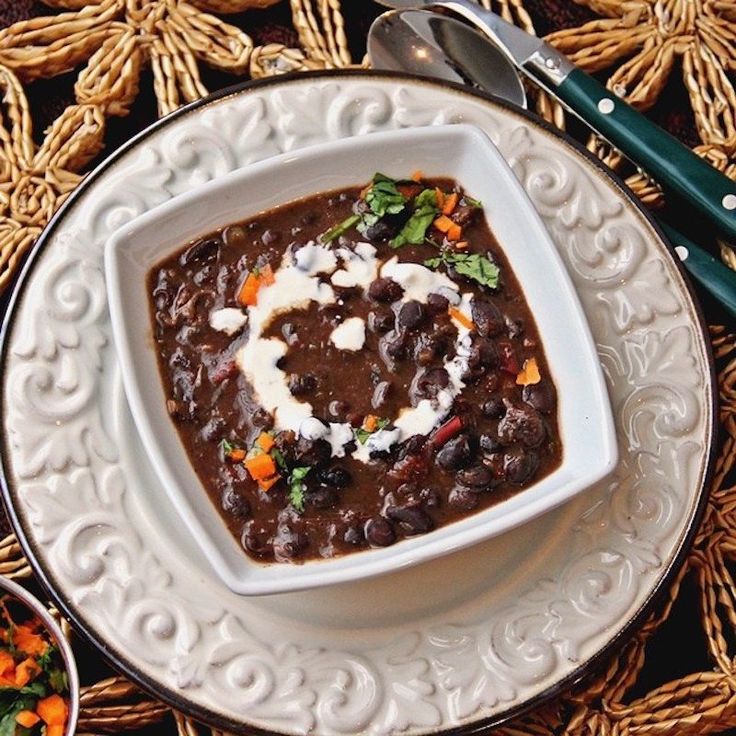 a white plate topped with black beans covered in sour cream