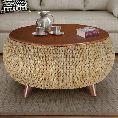 a wicker coffee table sitting on top of a rug in front of a couch