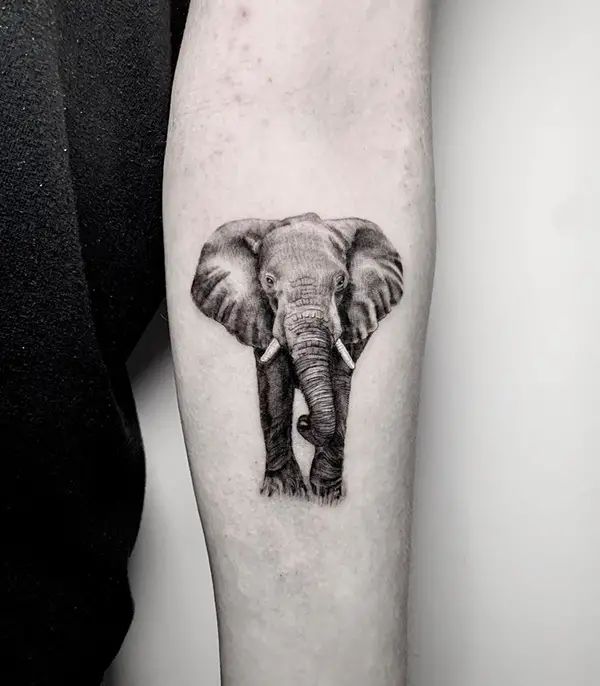 an elephant tattoo on the right forearm and leg, it is in black and white