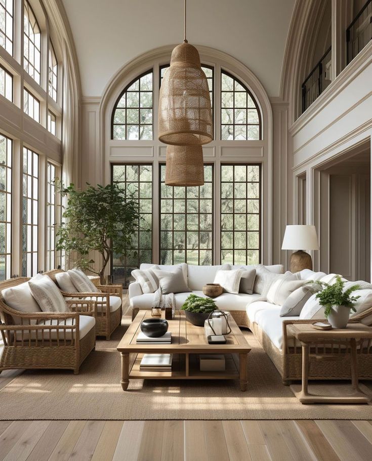 a living room filled with lots of furniture next to large windows and wooden flooring