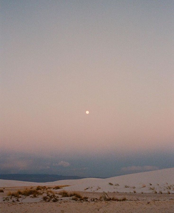 the moon is setting over some sand dunes