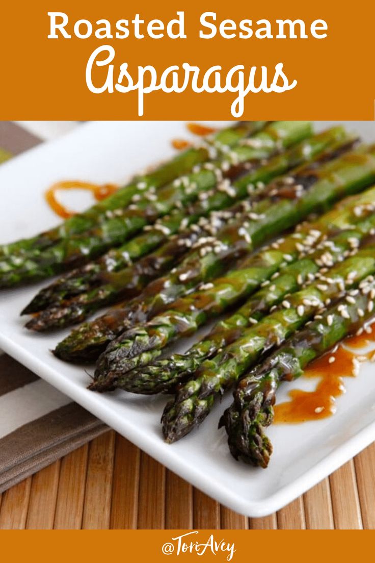 roasted sesame asparagus on a white plate with brown sauce drizzled over them