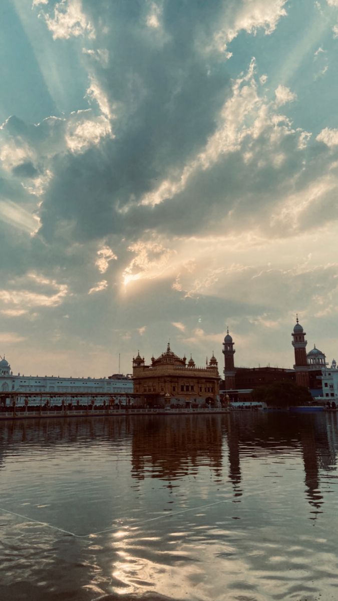 the sky is reflected in the water and clouds are seen over the buildings on the other side