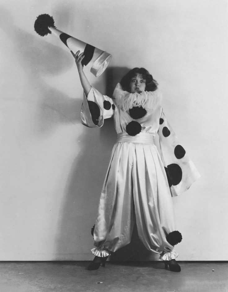 an old photo of a woman dressed in costume and holding two hats on her head