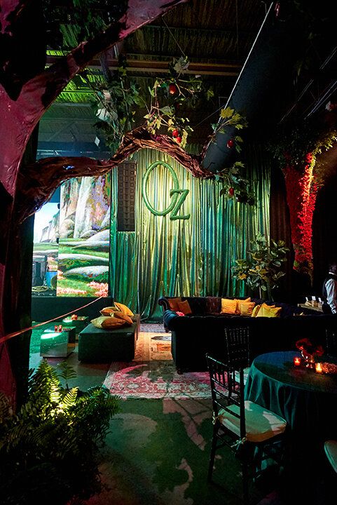 a room filled with lots of plants and furniture next to a wall covered in green curtains