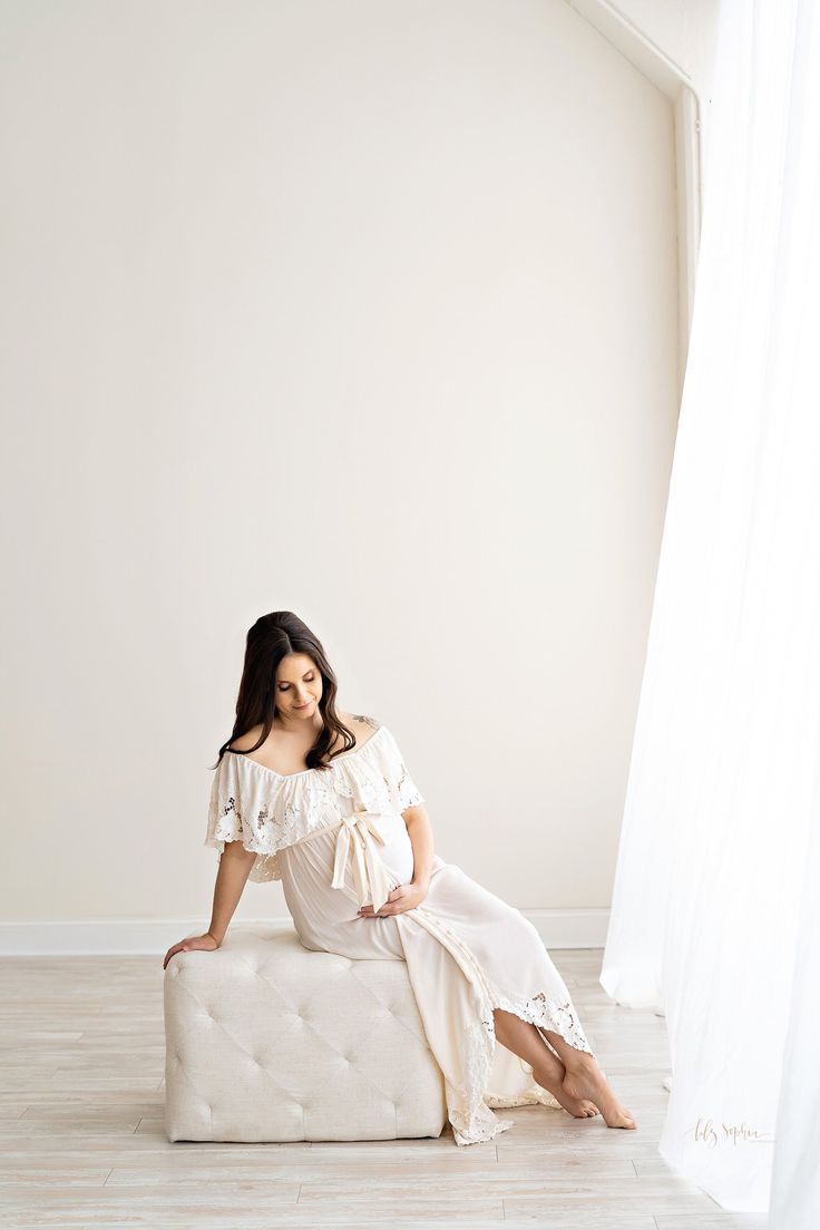 a woman sitting on top of a bed in a room with white walls and wooden floors