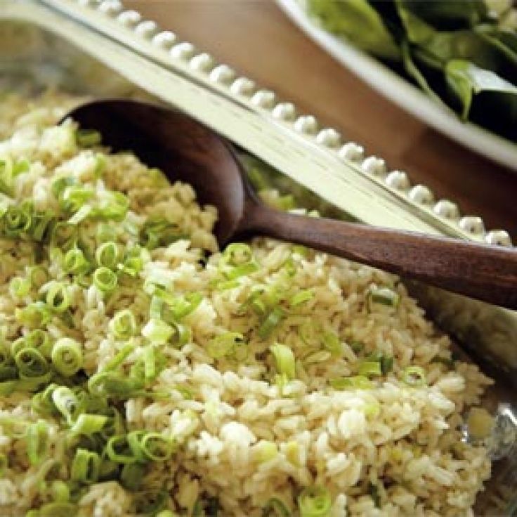 rice and broccoli are mixed together in a bowl with a wooden spoon on the side