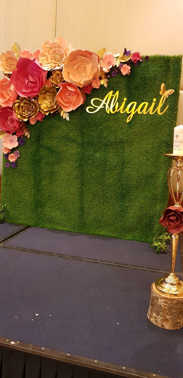 an arrangement of flowers and candles on top of a table with a sign in the background