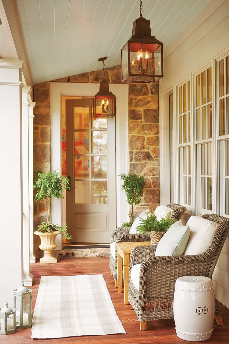 a porch with wicker furniture and potted plants on the front door sill