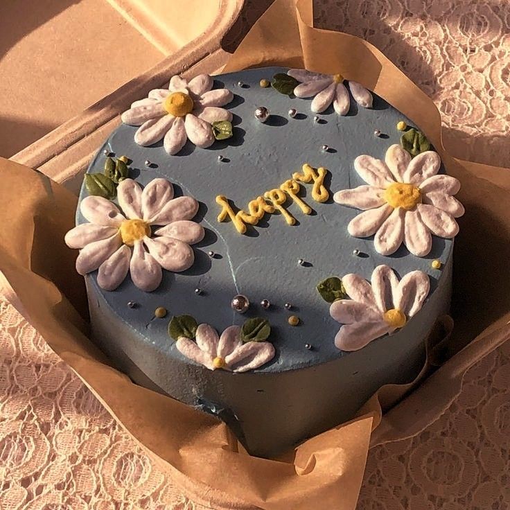 a blue cake with white flowers on it and the word happy spelled in gold letters