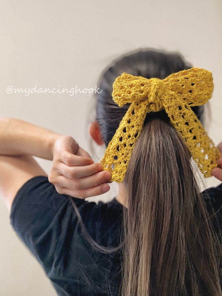 a woman with long hair wearing a yellow crochet bow in front of her head