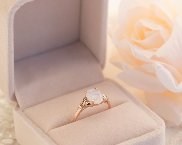 This is an oval moonstone ring, vintage style moonstone engagement ring, solitaire ring, moonstone engagement ring, gemstone ring, moonstone gold ring, oval engagement ring, a perfect moonstone engagement ring. This vintage style floral ring and has a dainty and feminine design, a solitaire vintage style with a natural oval rainbow moonstone, that symbolizes passion and endless love. This unique engagement ring is the best way to show your pure love for the one you love. ♥ Moonstone Gemstone mea Fine Jewelry Oval Moonstone Ring With Rose Cut Diamonds, White Oval Moonstone Ring With Rose Cut Diamonds, Oval Opal Ring With Rose Cut Diamonds For Gift, Elegant Oval Cabochon Moonstone Ring For Anniversary, Elegant White Moonstone Ring, Oval Cabochon, Oval Opal Ring With Rose Cut Diamonds For Promise, Elegant White Moonstone Ring With Oval Cabochon, Elegant Oval Moonstone Ring With Center Stone, Elegant Oval Cabochon Moonstone Ring