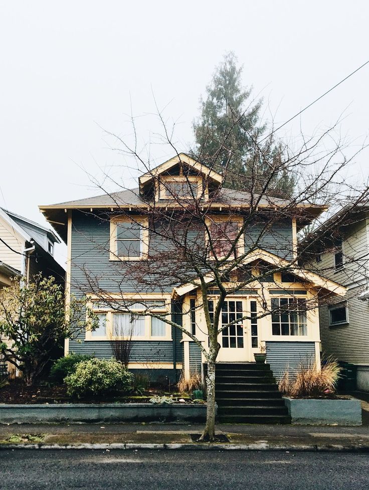 a house with stairs leading up to the front door and trees in front of it